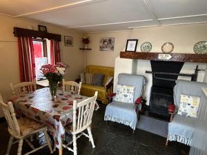 a living room with a table and chairs and a fireplace at Cummins Cottages in Ballycrossaun
