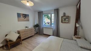 a bedroom with a bed and a chair and a window at Apartament LUA in Ustka +4 photos