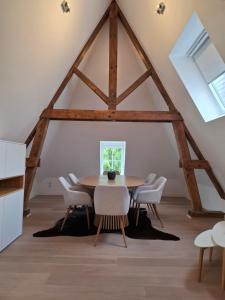 a dining room with a wooden table and white chairs at Un Toit sur les Monts in Tilff