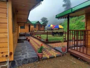 a porch of a house with a patio with umbrellas at LaSerene The Cottage - Pangot in Nainital