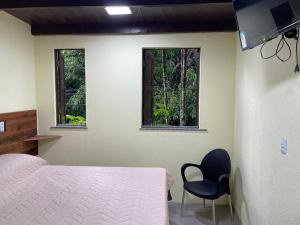 a bedroom with a bed and a chair and two windows at Casa Sankofa de Belém in Belém