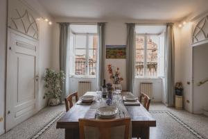 a dining room with a wooden table and some windows at Residenza d'Epoca " Il Campo" by FrancigenaApartments in Siena