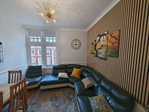 a living room with a leather couch and a table at High Street 3BR city views near beach - Groups, Families, Contractors in Bournemouth