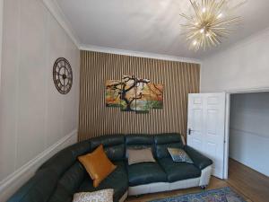 a living room with a green couch and a chandelier at High Street 3BR city views near beach - Groups, Families, Contractors in Bournemouth +12 photos