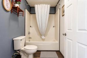 a bathroom with a white toilet and a bath tub at Big South Fork Trail Lodge Stearns in Stearns