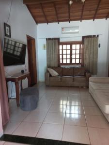 a living room with a couch and a tv at Chalé casa na mata Jasmim in Guararema