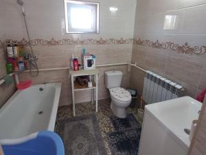 a bathroom with a toilet and a tub and a sink at Beksultan guest house in Epkin +38 photos