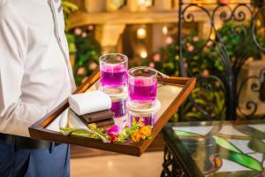a man holding a tray with two glasses and a box of candles at Happy Life Grand Hotel & Rooftop Skybar in Ho Chi Minh City