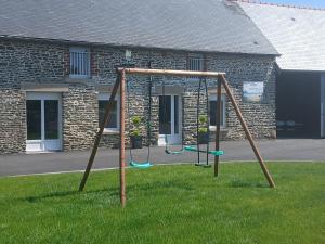 a swing set in the grass in front of a building at Les mouettes in Huisnes-sur-Mer