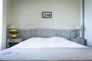 a bedroom with a white bed with two tables and two lamps at Les quatre vents in Luc-sur-Mer