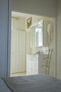 a white kitchen with a sink and a counter at Les quatre vents in Luc-sur-Mer