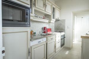a kitchen with white cabinets and a microwave at Les quatre vents in Luc-sur-Mer
