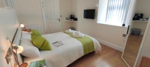 a bedroom with a bed with green and white pillows at Chandler's Lodge B&B in Camelford
