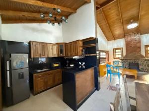 a kitchen with wooden cabinets and a black refrigerator at villa regazo de paz in Concepción de La Vega