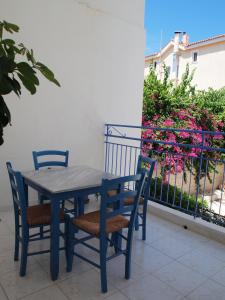 Ionion Apartments في سكالا كيفالونياس: طاولة زرقاء وكراسي على شرفة بها زهور