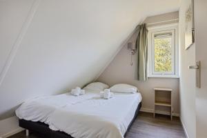 a bedroom with a bed with white sheets and a window at Bungalowpark Hoge Hexel in Hoge-Hexel +59 photos