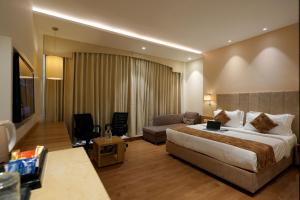 a hotel room with a bed and a couch at Celebrant Hotel in Varanasi