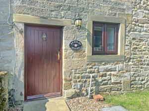 a stone building with a red door and a window at Bradley House in Harrop Fold