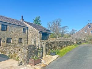 a stone building with a gate next to a street at Bradley House in Harrop Fold