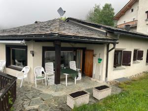 a patio with chairs and a table and a house at Pedecosta in Poschiavo