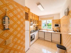 a kitchen with yellow tiles on the wall and a window at Troia Apartments in Troia
