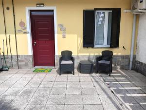 a group of chairs sitting in front of a red door at Sleep & Fly Studio Smart in Case Nuove