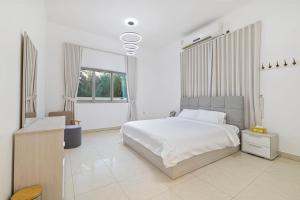 a white bedroom with a bed and a window at Best chalet 4 BHK for group gatherings with beach access and private pool in Fujairah
