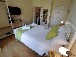 a bedroom with a large white bed with green pillows at Chandler's Lodge B&B in Camelford