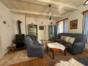 a living room with two chairs and a couch and a stove at Chalupa V soukromí - Chřibská in Chřibská