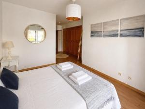 a white bed in a room with a mirror at Troia Apartments in Troia +16 photos