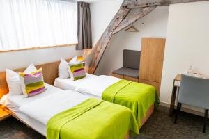 a hotel room with two beds and a chair at Kloster Heidberg in Eupen +17 photos