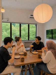 a group of people sitting around a table eating pizza at Jiran Hostel Kota Kinabalu in Kota Kinabalu