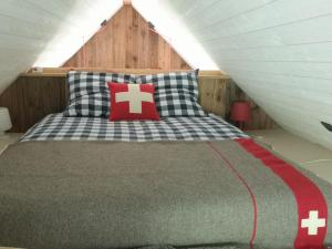 a bed with a red cross pillow on top of it at la Petite Grange Escouaraou in Melles