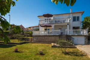 a large white house with a balcony and umbrella at Apartments Anka in Krk
