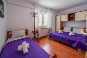 two beds in a room with purple sheets at Apartments Anka in Krk