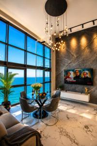 a living room with a tv and a table and chairs at Penthouse Panorama Luxury Sea View Premium Stay in Batumi in Batumi