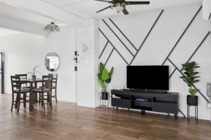 a living room with a tv and a table with chairs at Arcadian Place in Port-of-Spain