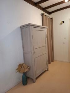 a white cabinet in a room with a vase at AGREABLE APPARTEMENT in Eaux-Bonnes