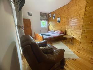 a living room with a leather chair and a bed at Agroturystyka Świt dobry in Strzebowiska