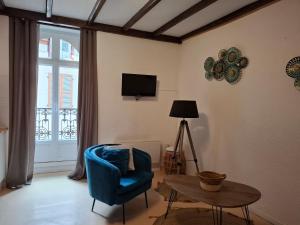 a living room with a blue chair and a table at AGREABLE APPARTEMENT in Eaux-Bonnes