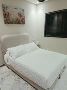 a white bed in a white room with a window at App najoua in Safi