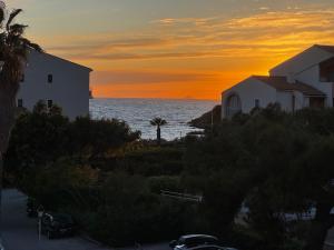 a sunset over the ocean and a white building at Appartement avec vue sur la mer in Six-Fours-les-Plages