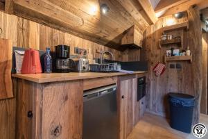 a kitchen with wooden walls and a counter with a dishwasher at la Petite Grange Escouaraou in Melles
