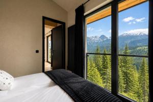 a bedroom with a bed and a large window with mountains at Tatry Residence SPA in Kościelisko