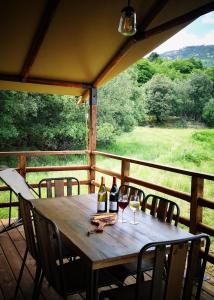 a wooden table with two bottles and two glasses of wine at Domaine l Alba Scelta in Ucciani
