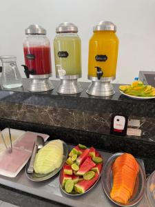ein Buffet mit Tellern voller Obst und Gemüse und Saft in der Unterkunft Hotel Pousada Colliseu in Aparecida + 114 Fotos