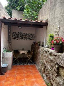 a patio with a table and flowers on a stone wall at Casa rural Chantal in San Martín de Trevejo