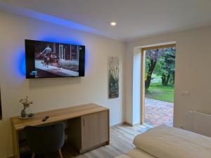 a bedroom with a desk and a tv on the wall at Landhotel Biberburg in Bad Liebenwerda