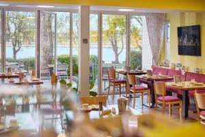 a restaurant with tables and chairs and large windows at Iris am See garni in Radolfzell am Bodensee