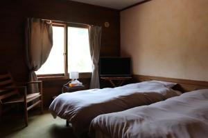 a hotel room with two beds and a window at Yamagata Zao Pension Apron Stage in Kaminoyama
